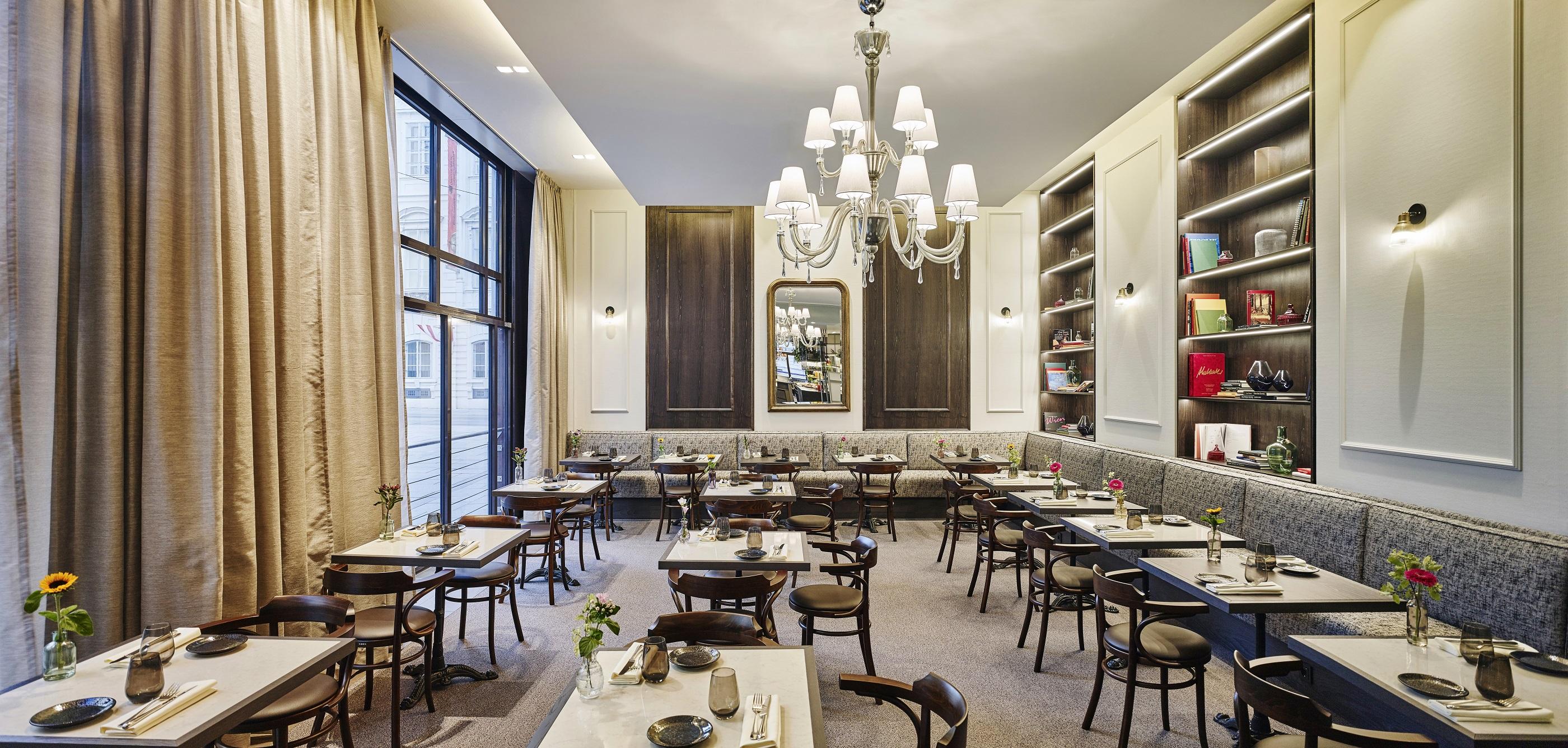Steigenberger Hotel Herrenhof Відень Екстер'єр фото The photo depicts the interior of an elegant restaurant. The space features a combination of large windows that allow natural light to flood in, enhancing the ambiance. The decor includes soft beige and gray tones, with a plush seating area that has 