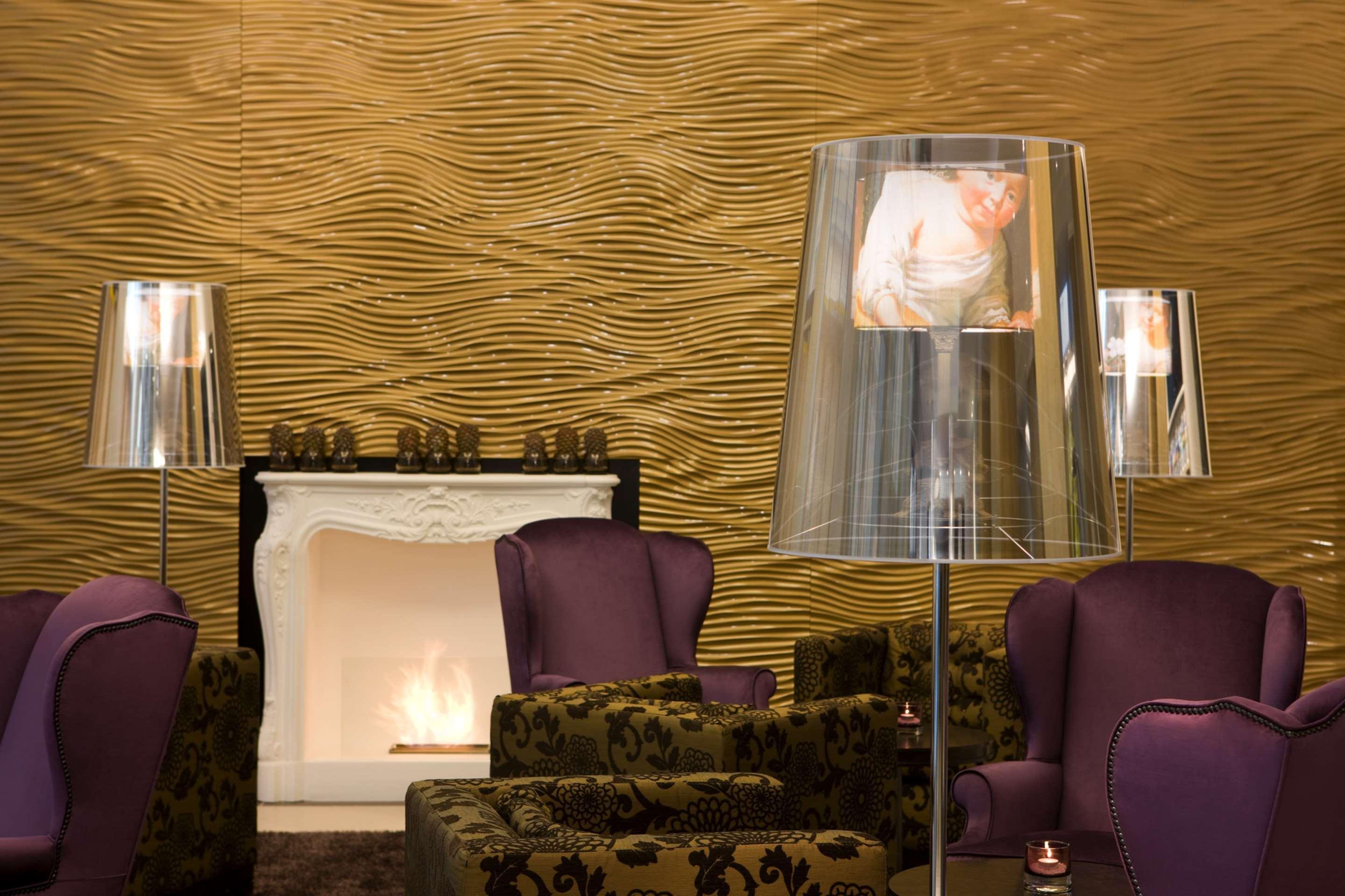 Steigenberger Hotel Herrenhof Відень Екстер'єр фото The photo shows a stylish and contemporary lounge area. The walls have a wavy texture in a golden color, creating an elegant backdrop. In the center, there are plush armchairs in varying shades of purple and intricate patterns, providing a comfortabl