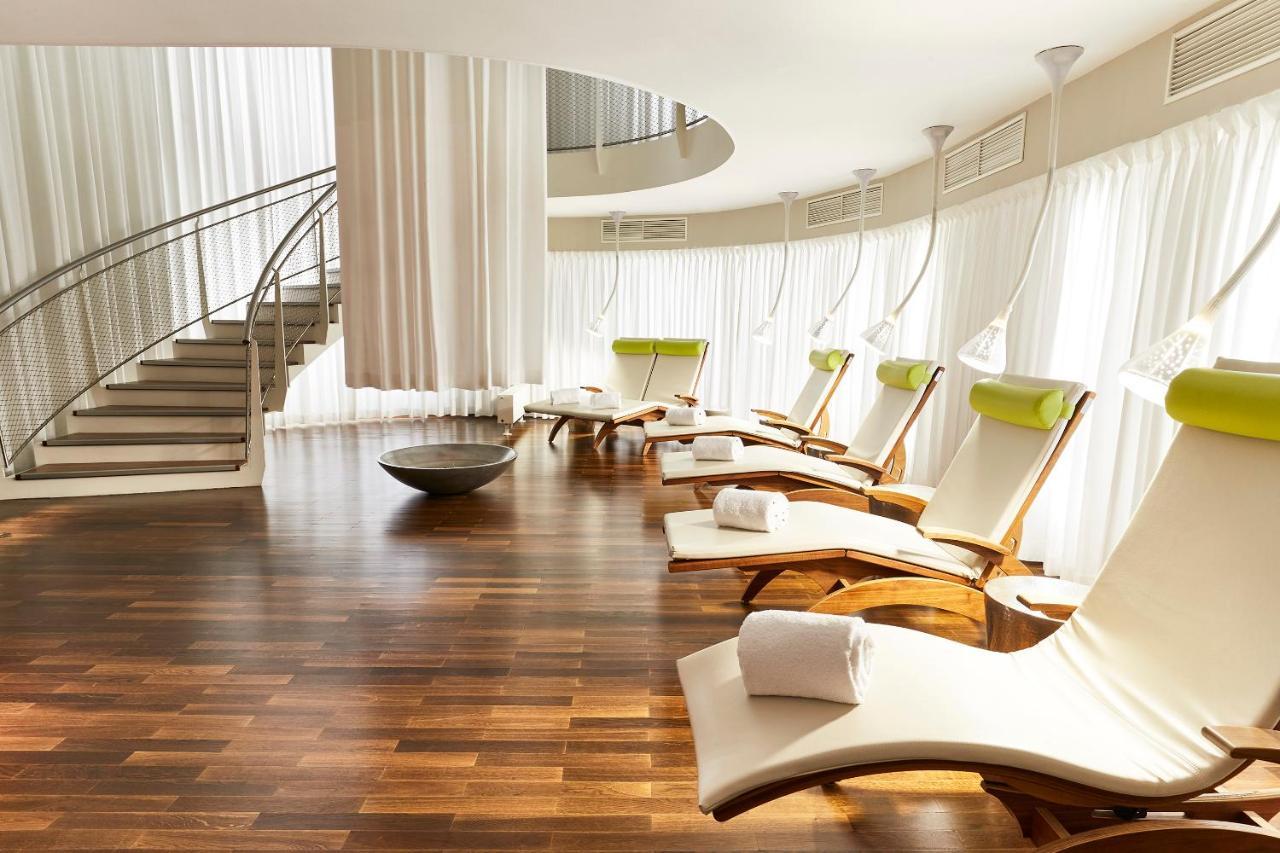 Steigenberger Hotel Herrenhof Відень Екстер'єр фото The photo shows a tranquil spa or relaxation area. It features several reclining lounge chairs with light-colored cushions, positioned alongside large windows draped with sheer white curtains that allow natural light to filter in. There is a round, d