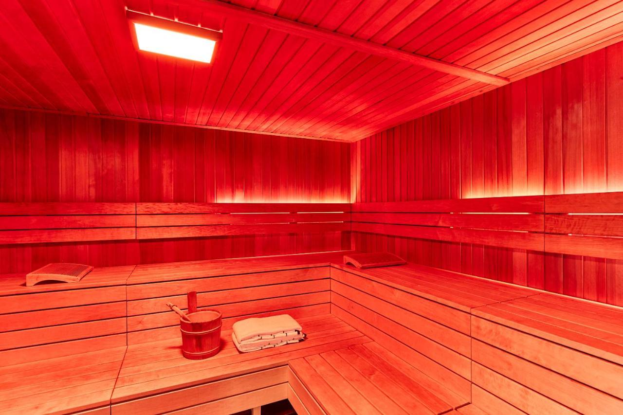 Steigenberger Hotel Herrenhof Відень Екстер'єр фото The photo shows the interior of a sauna. The space is predominantly wooden, featuring wooden benches and walls. The lighting is red, creating a warm and cozy atmosphere. There is a wooden bucket and ladle, which are typically used to pour water over 