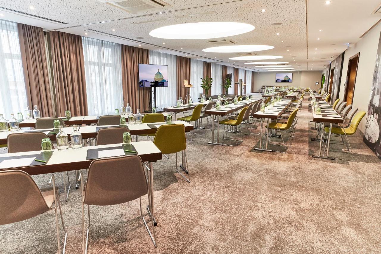 Steigenberger Hotel Herrenhof Відень Екстер'єр фото The photo depicts a modern conference room set up for a meeting or event. There are several long tables arranged in rows, each equipped with chairs. The tables are neatly arranged and have notepads and water bottles for attendees. Large windows allow