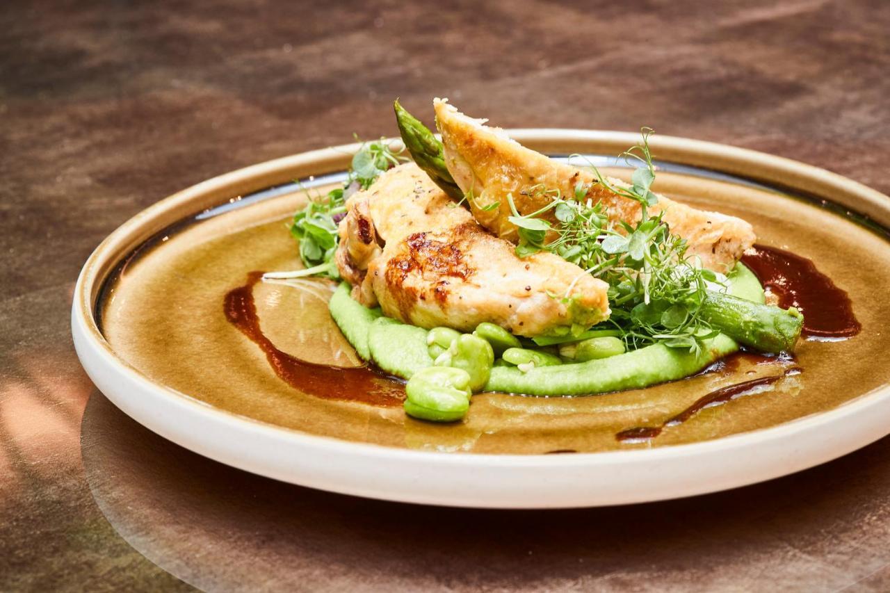 Steigenberger Hotel Herrenhof Відень Екстер'єр фото The photo showcases a plated dish featuring grilled chicken fillets, served on a bed of smooth green puree, likely made from peas or avocado. Accompanying the chicken are fresh green pea shoots and asparagus, adding vibrant colors and textures. A dri