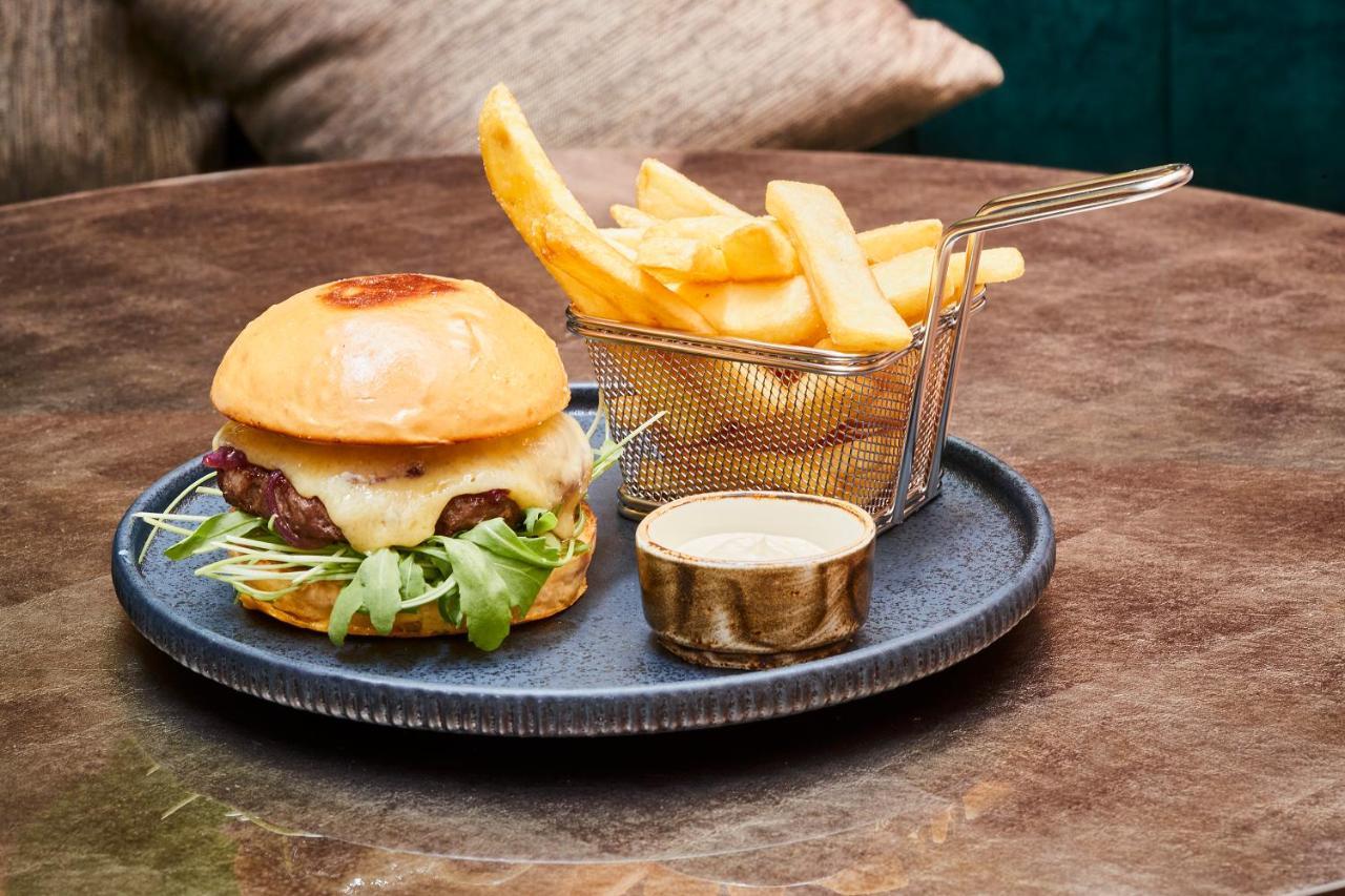 Steigenberger Hotel Herrenhof Відень Екстер'єр фото The photo shows a delicious meal consisting of a hamburger and French fries. The hamburger is served on a round plate and features a soft, shiny bun filled with ingredients like a beef patty, possibly cheese, lettuce, and other toppings. Next to the 