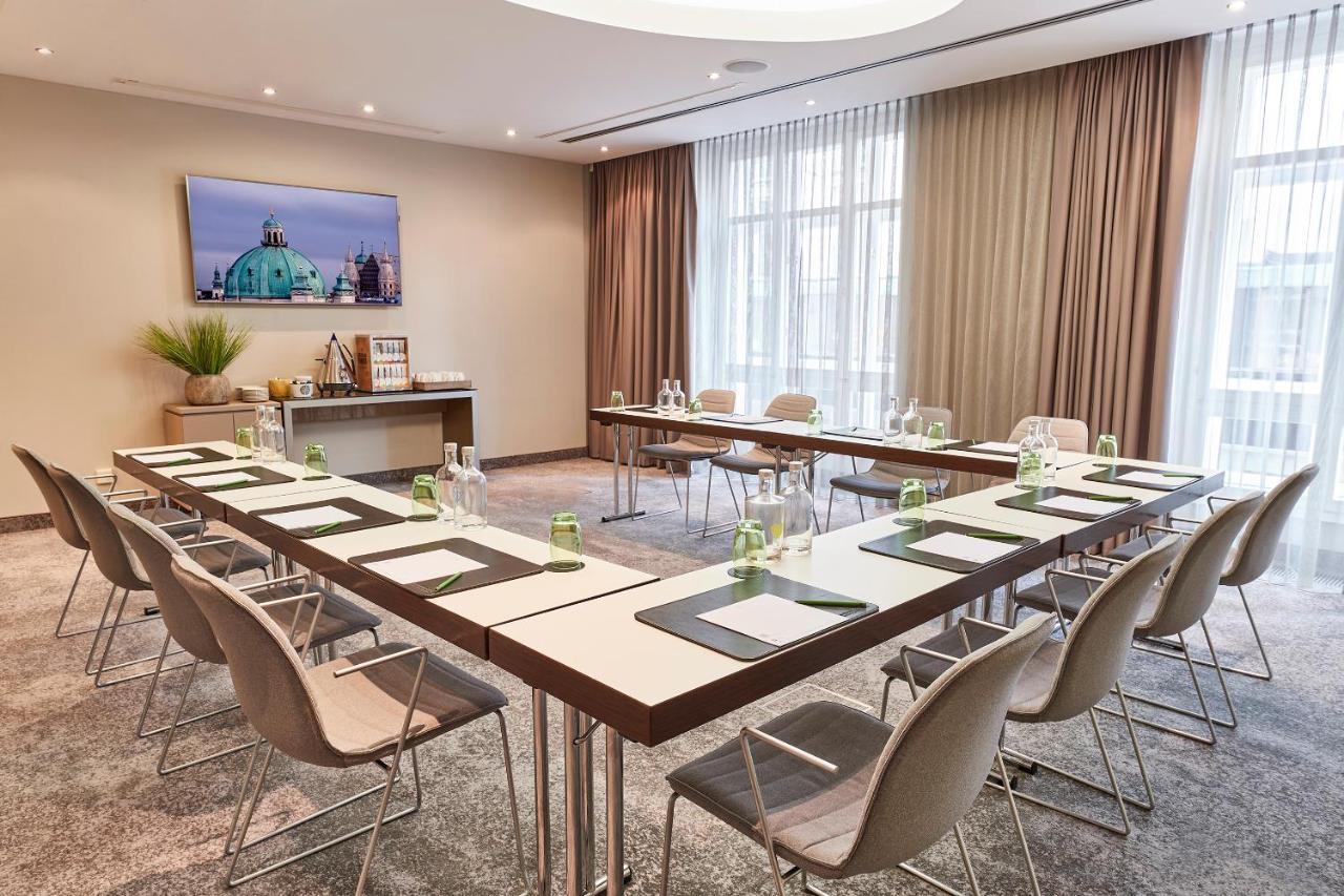 Steigenberger Hotel Herrenhof Відень Екстер'єр фото The image shows a modern meeting room configured for a business presentation or gathering. The room features a large, rectangular table arranged with neatly placed folders and water bottles. There are several ergonomic chairs around the table. The wa