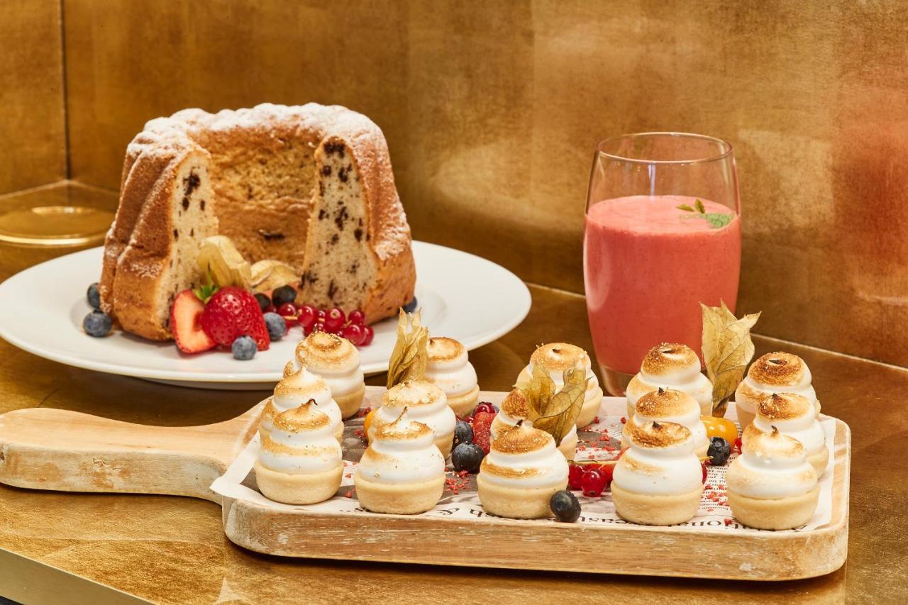 Steigenberger Hotel Herrenhof Відень Екстер'єр фото The photo showcases a delightful assortment of desserts. 

On the left, there is a round loaf cake, possibly a fruitcake, decorated with powdered sugar and surrounded by fresh berries like strawberries and blueberries. 

In the foreground, there is a
