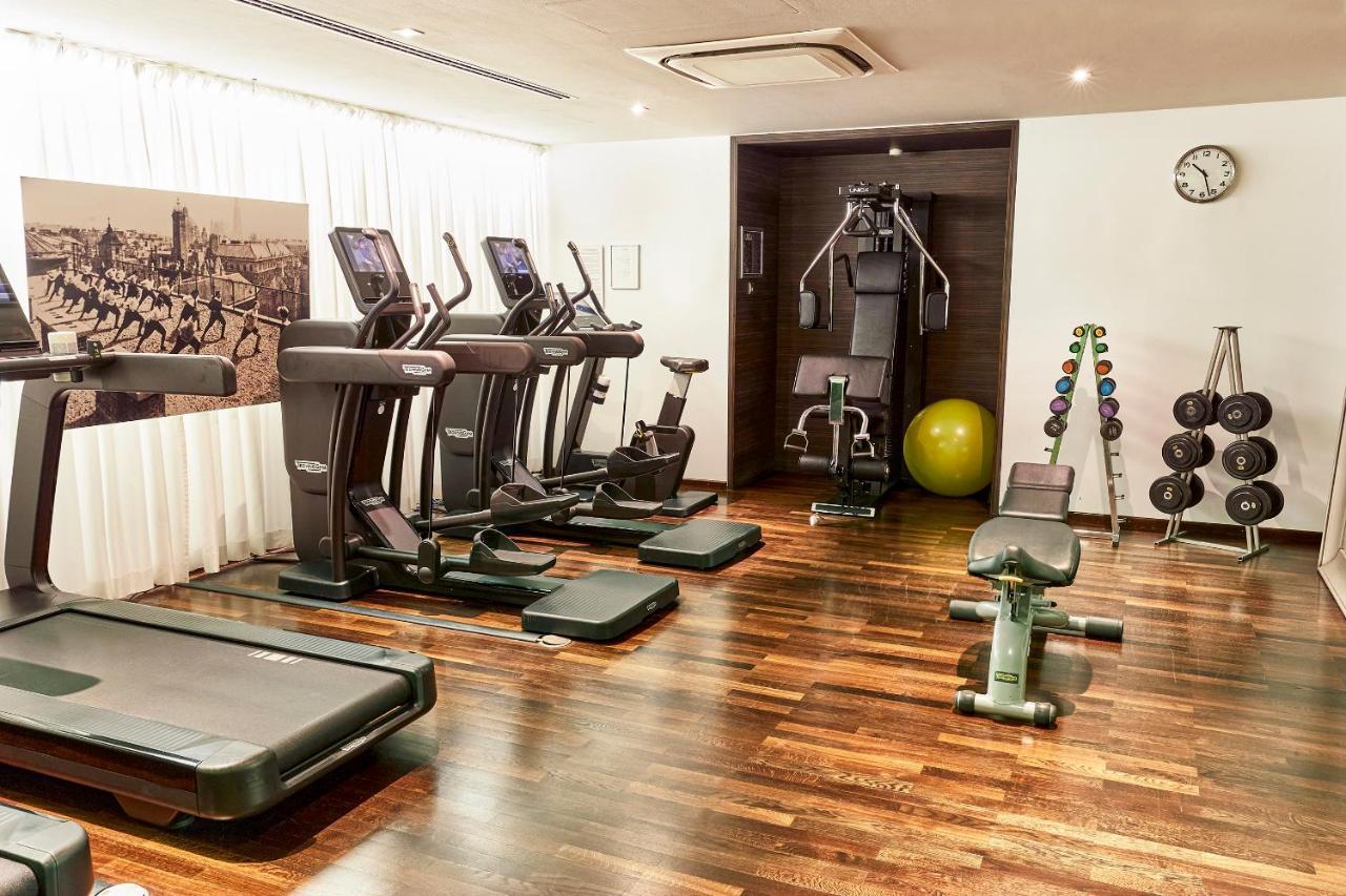 Steigenberger Hotel Herrenhof Відень Екстер'єр фото The photo shows a modern gym or fitness room. Inside, there are several exercise machines, including treadmills and an elliptical machine. There is also a multi-gym setup for weight training, a bench for exercises, and a stability ball. The flooring 