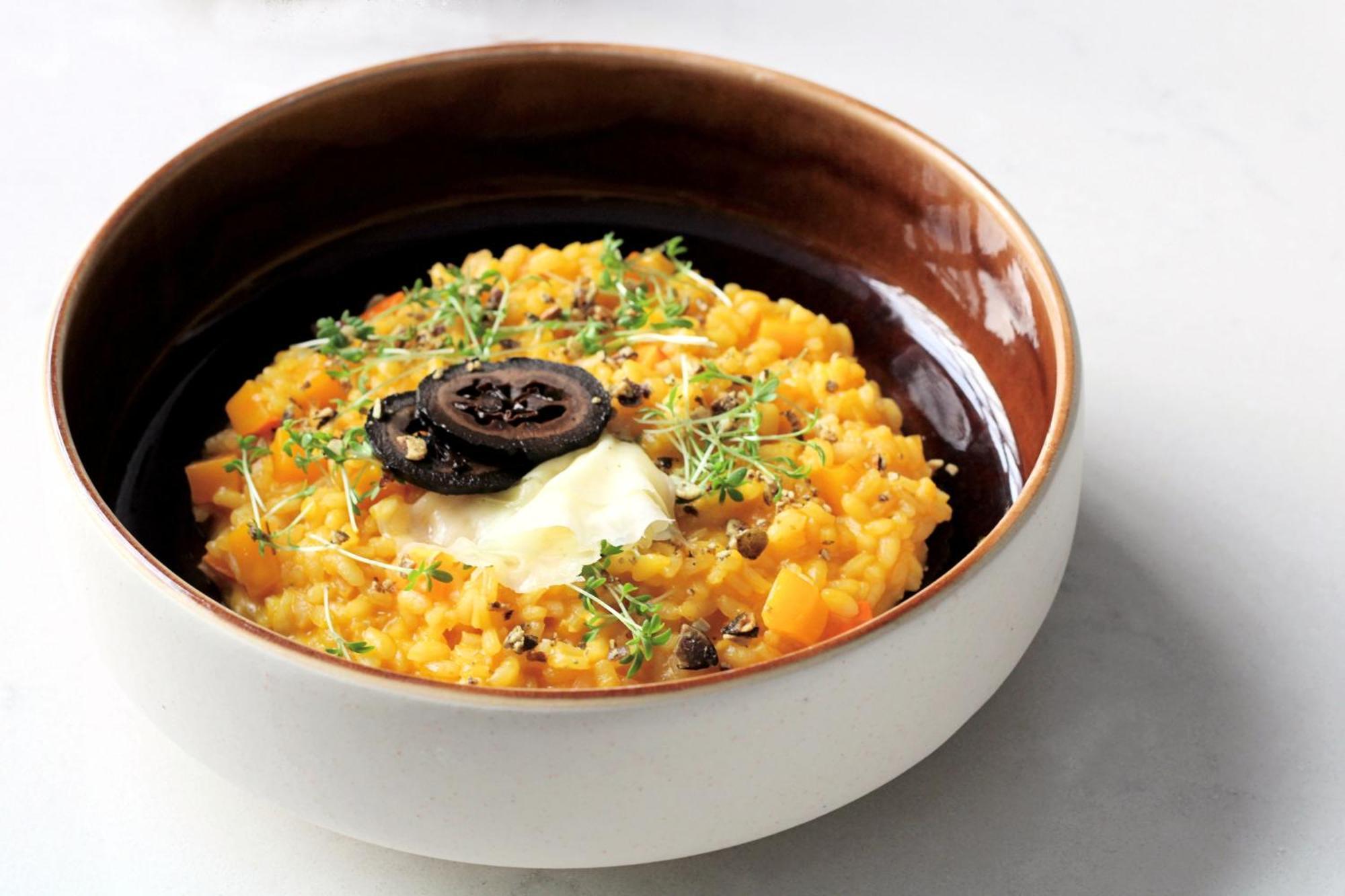 Steigenberger Hotel Herrenhof Відень Екстер'єр фото The photo shows a bowl of creamy risotto or a similar dish, featuring a base of vibrant yellow or orange rice, possibly made with squash or pumpkin. The dish is garnished with freshly chopped herbs, adding a touch of green. At the center, there is a 